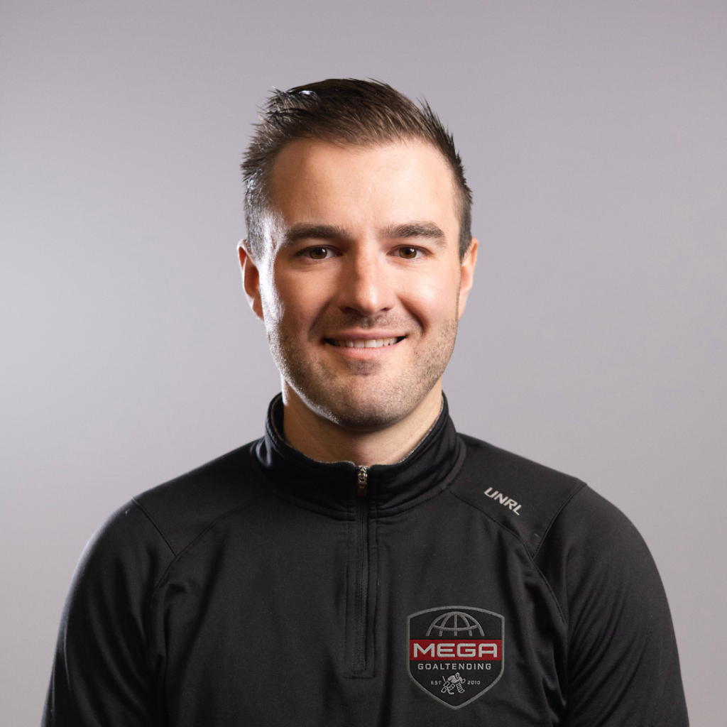Young man smiles at camera, wearing a black zipped sports jacket against a neutral gray studio background.