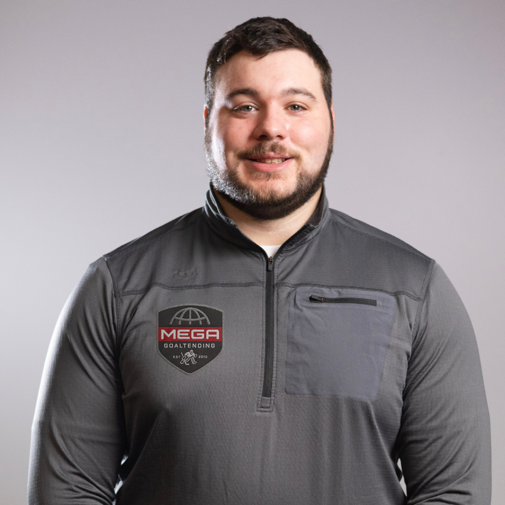 Man smiles, wearing a gray pullover with a logo, posing against a neutral studio backdrop.